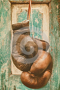 Pair of vintage boxing gloves hanging on a weathered ancient wooden door