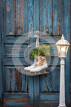 Pair of vintage white Ice Skates with Christmas decoration hanging on the blue rustic door and a big lantern