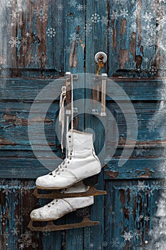 Pair of vintage white Ice Skates hanging on the blue rustic door