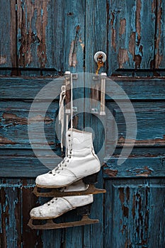 Pair of vintage white Ice Skates hanging on the blue rustic door