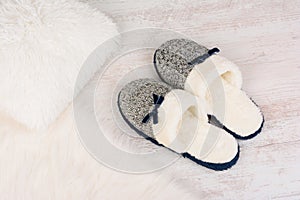 Pair of warm female slippers on white furry carpet photo