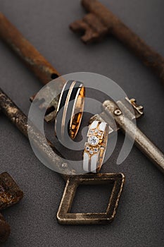 Pair of wedding enamel rings on gray background with vintage rusty keys