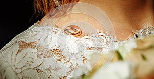 A pair of wedding rings of the bride and groom on the shoulder of the future wife in a white dress. Wedding accessories, ceremony,