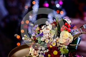 Pair of wedding rings lying on a colorful bouquet with different flowers over the blurred background