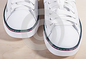 Pair of White Fashionable Laced Trainers On Wooden Surface