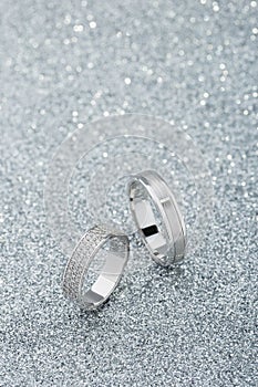 Pair of white gold wedding rings with diamonds on sparkle background