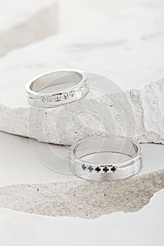 Pair of white gold wedding rings with diamonds on white textured background