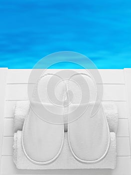 Pair of white hotel / home/ spa / wellness slippers with rolled towels.