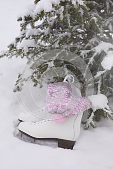 Pair of White Ice Skates with as pink scandinavian pompon hat in snow