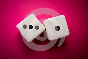 Pair of white plush dices on the pink background