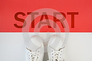 A pair of white sneakers in front of the start line with the word start printed on a red background. Step into the Future