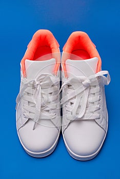 Pair of white sneakers isolated on blue background. Sport shoes.