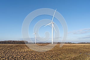 A pair of wind turbines spin in an open field