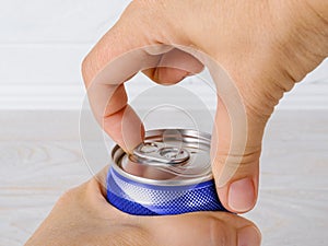 Pair of woman hands opening a can of soda or beer close-up. Drinking on the go beverages in aluminum cans with pull tabs