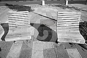 A pair of wooden benches on the sidewalk with long ones in black and white.