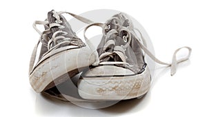 A pair of worn out gray sneakers on a white background