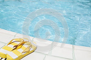 Pair of yellow flip flops by the pool side