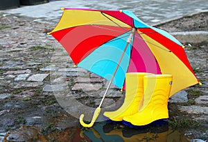 Pair of yellow rubber boots with an open umbrella