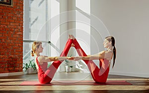 Pair yoga asana. Young women in sports uniforms do beautiful pair asana navasana in yoga studio