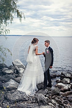 A pair of young newlyweds on the stones by the big river