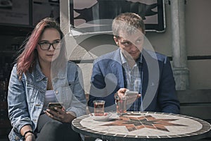 Pair of young people a man and a girl are sitting at a table of