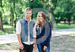 Pair of young people standing in park and hold hands