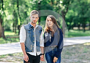 Pair of young people standing in park and hold hands