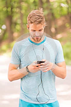 Pairing his fitness watch with his smartphone. Sportsman using fitness tracker for training outdoor. Fit man tracking