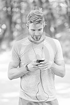 Pairing his fitness watch with his smartphone. Sportsman using fitness tracker for training outdoor. Fit man tracking