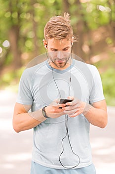 Pairing his fitness watch with his smartphone. Sportsman using fitness tracker for training outdoor. Fit man tracking