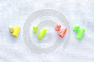 Pairs of earplugs against noise in different colors isolated on white background.