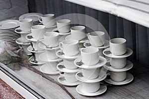 pairs of mugs and plates with spoons in the window of the tableware store