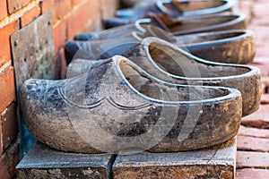 Pairs of old used dutch traditional wooden shoes or clogs in a row