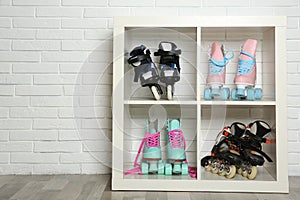 Pairs of roller skates on shelves near white brick wall.