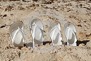 Pairs of white sandals in the sand at the beach