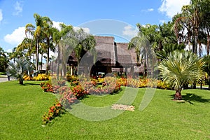 Paisagismo tropical com jardins, construÃ§Ãµes coloridas ao fundo cercadas por muita vegetaÃ§Ã£o