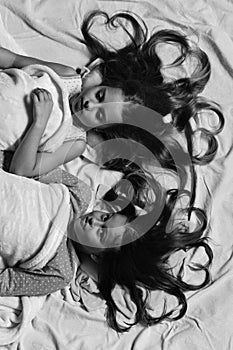 Pajama party and childhood concept. Girls lie on white and pink bed sheets