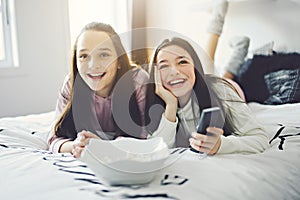 A pajama party with teens eat popcorn on the bed