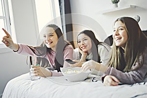 A pajama party with teens eat popcorn on the bed