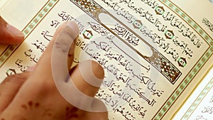 Pakistan, India, Asia And Indonesia. 11 May 2022. young woman reading the quran in arabic. close up to finger and quran.