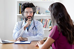 Pakistani male doctor listening to female patient