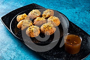 Pakistani spicy gol gappay, indian pani puri and bangali fuchka full of chaat masala with sour water in a dish isolated on marble