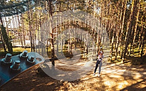 Palanga, Lithuania - 2023: young woman girl sliding along zipline in fir tree forest in summer. Lithuania adventure park in HBH