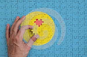 Palau flag is depicted on a puzzle, which the man`s hand completes to fold