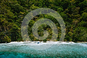 Palawan, Philippines, El Nido. Aerial drone view of a secluded deserted tropical beach with lonely tourist boat in frost