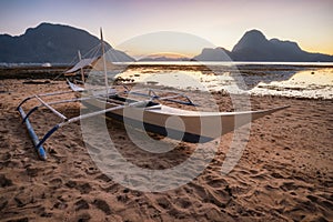 Palawan, Philippines. El Nido shore beach with local banca boat with picturesque sunset golden light scenery and island