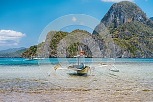 Palawan, Philippines. Traditional filippino banca boat in shallow blue tropical lagoon in El Nido bay. Limestone