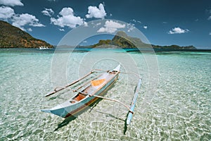 Palawan, Philippines. Traditional small fishing banca boat in front of Cadlao Island in crystal clear shallow water