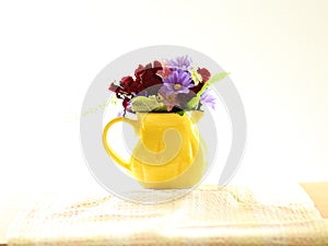 Small posy of spring flowers in a small, yellow jug. photo