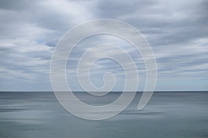 Pale cloudy sky over dim greyish sea water